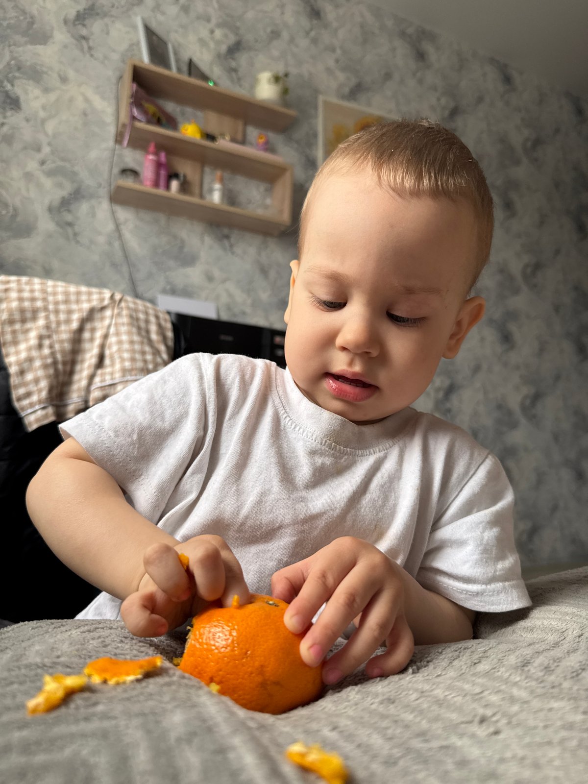 Child peels orange on sofa in Rusanovo morning scene