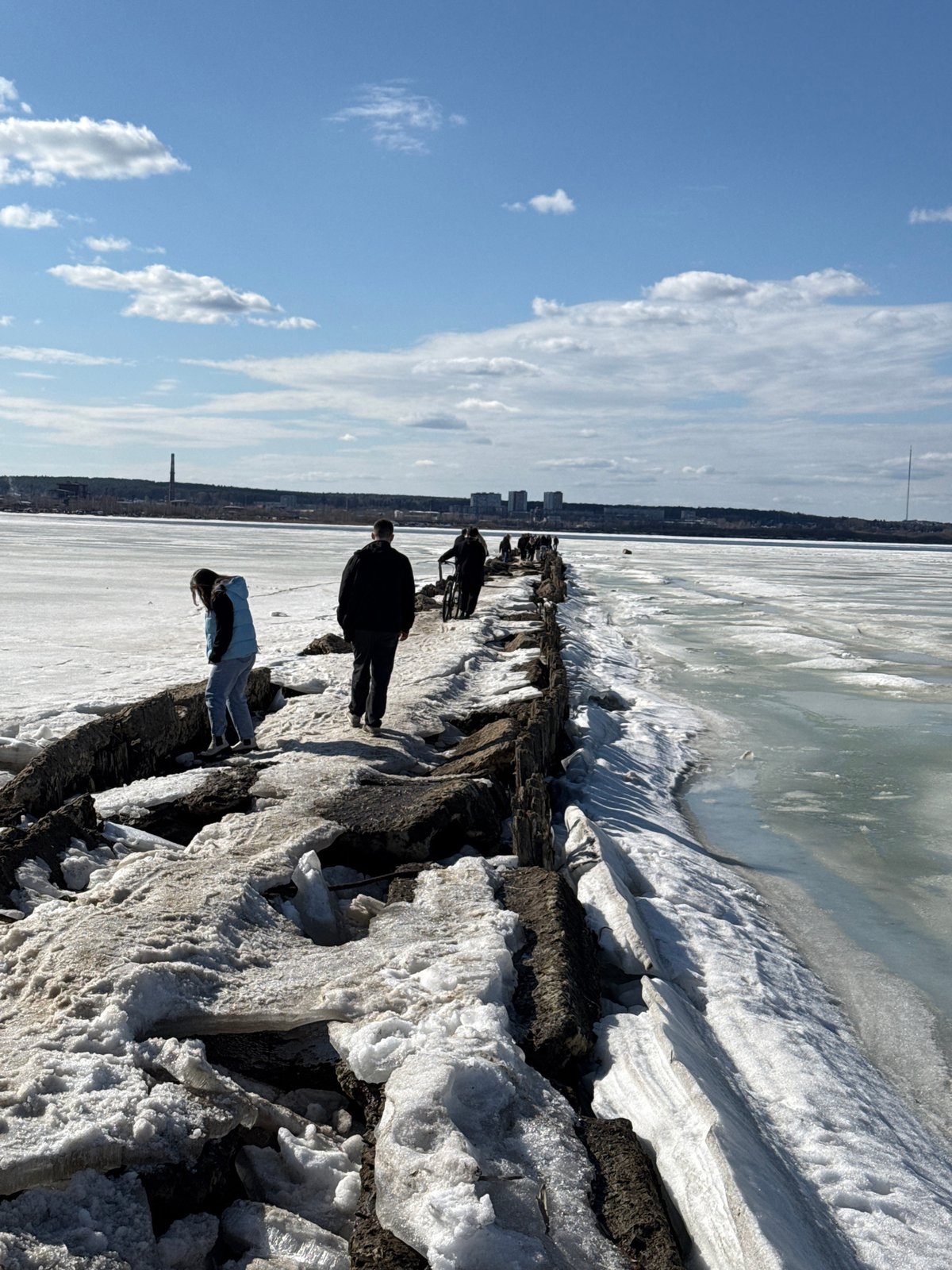 People walk on icy concrete structure near frozen water