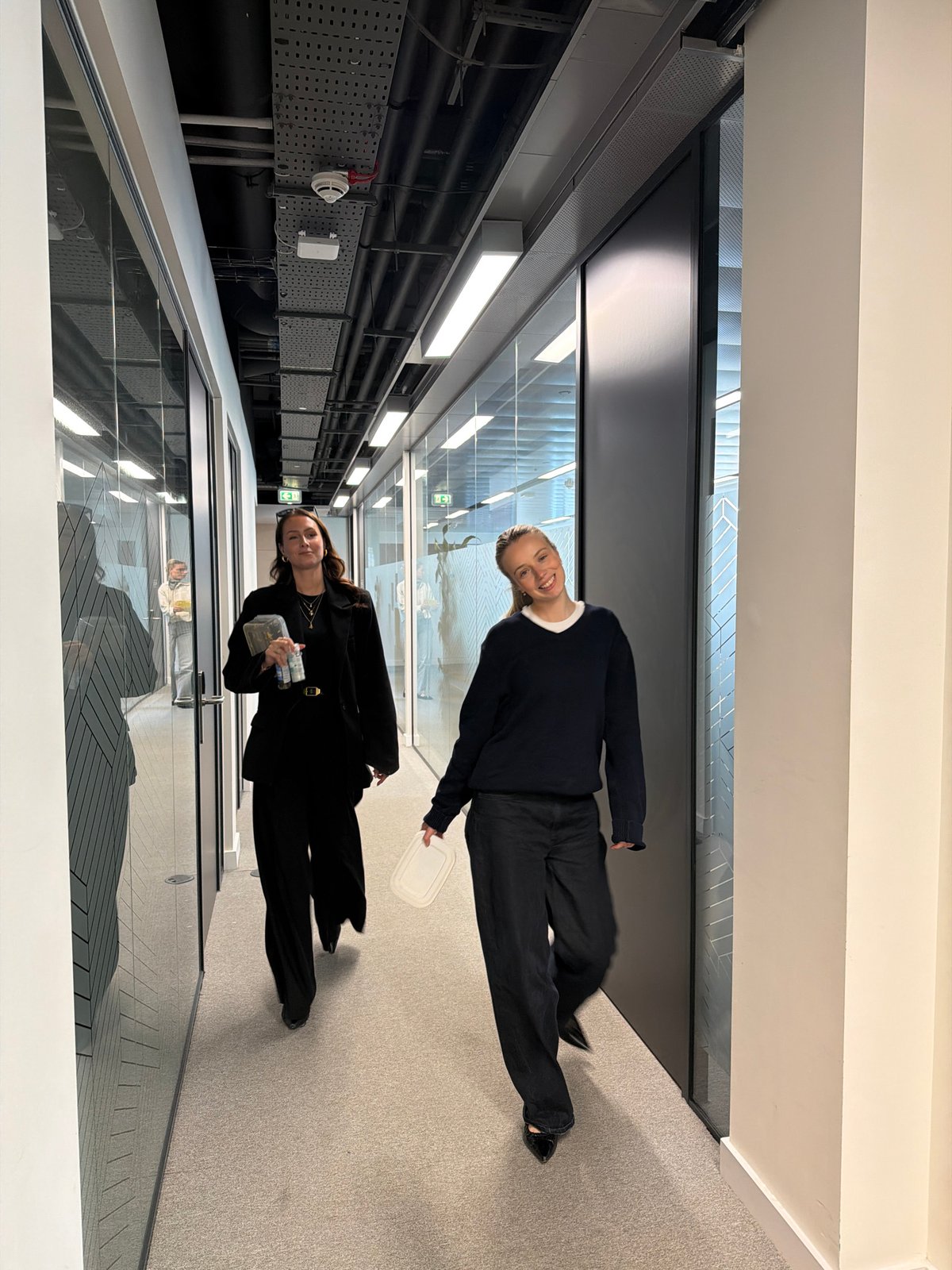 Two women photographed moving through London office building