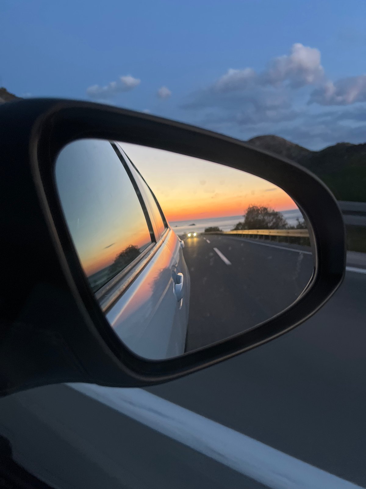 Driver captures sunset reflection in mirror while traveling Montenegro