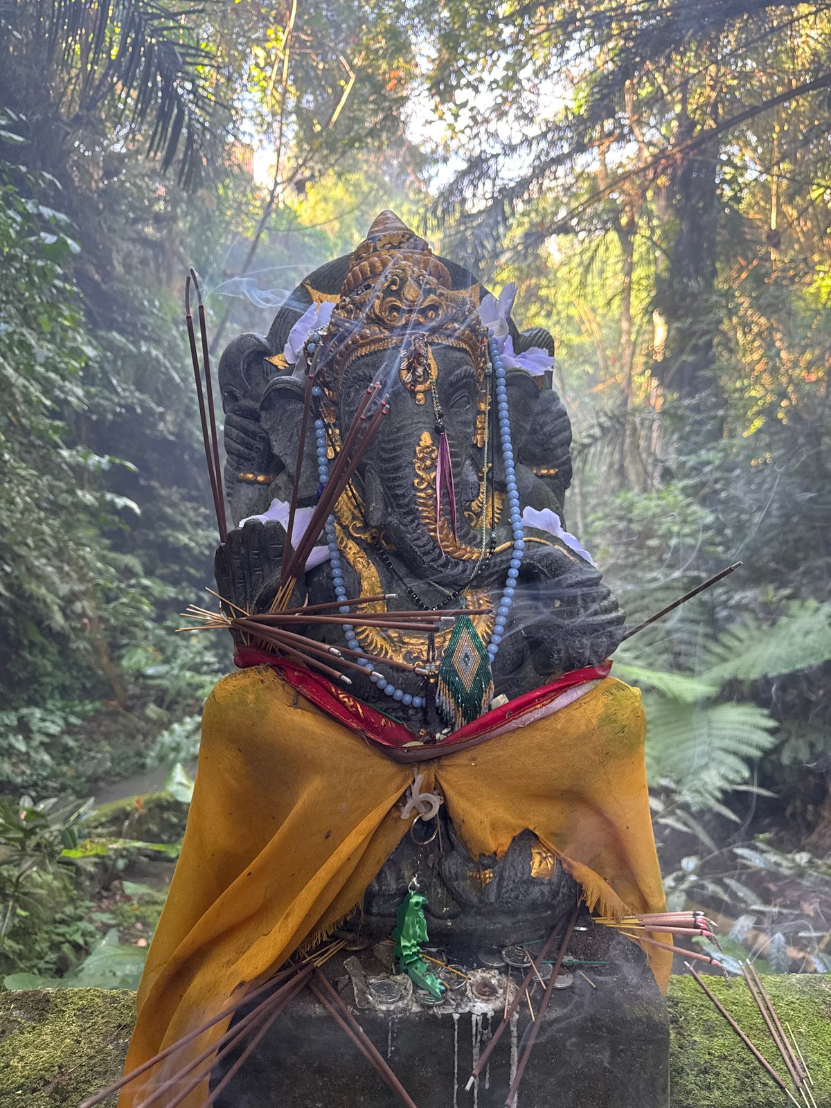 Decorated Ganesha shrine smoldering with incense in Ubud jungle
