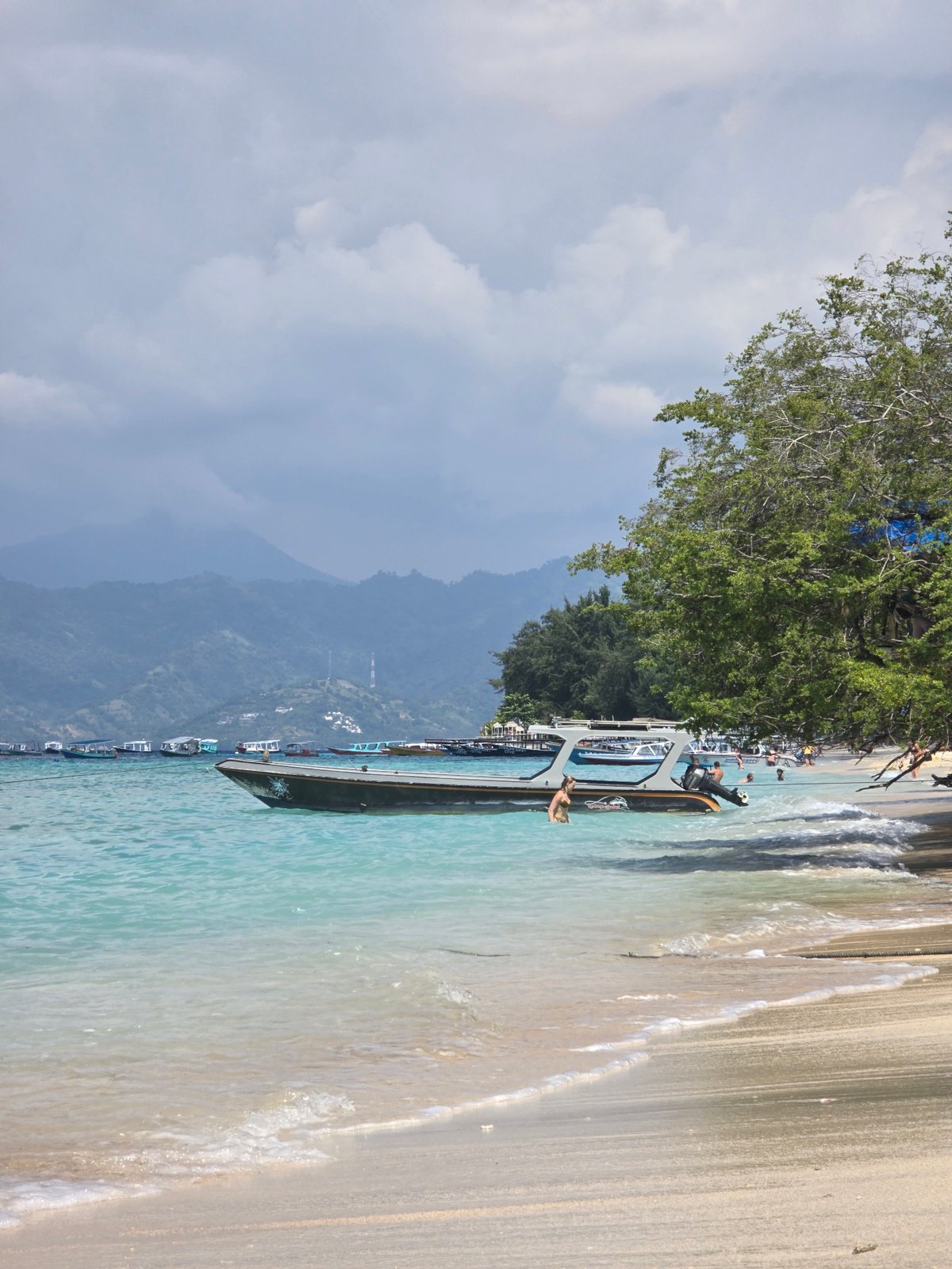 Morning beach scene captured in Indonesia with boats and swimmers