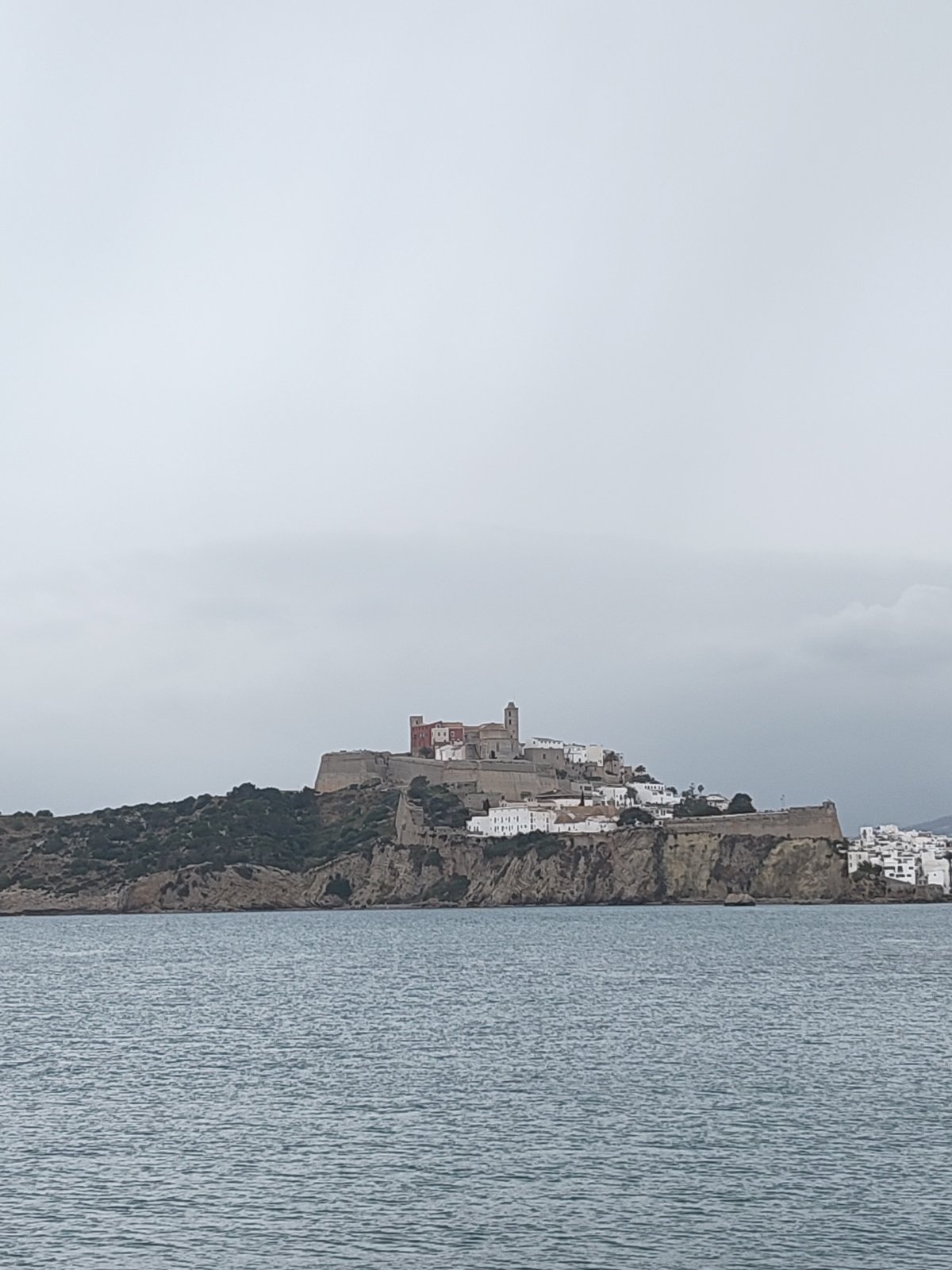 Coastal views of historic Ibiza and docked sailboat captured