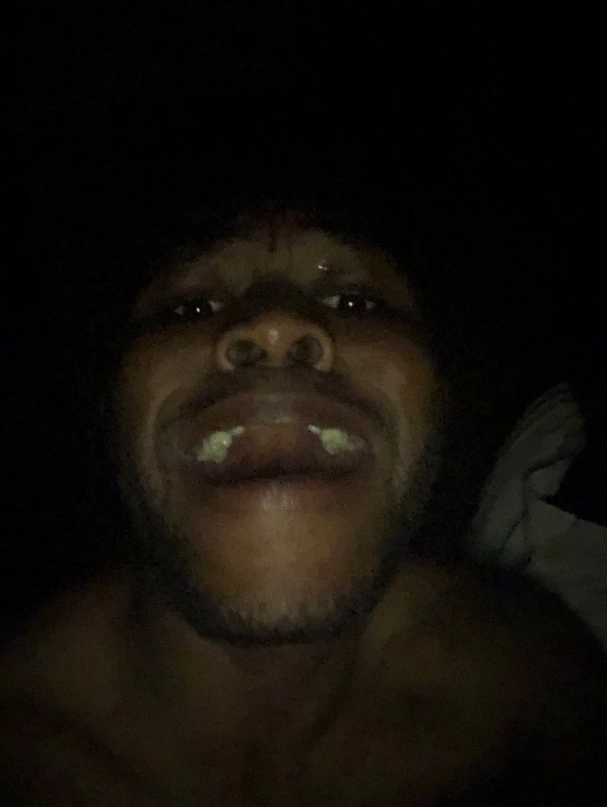 Man photographed making animated expressions in low-light selfie session