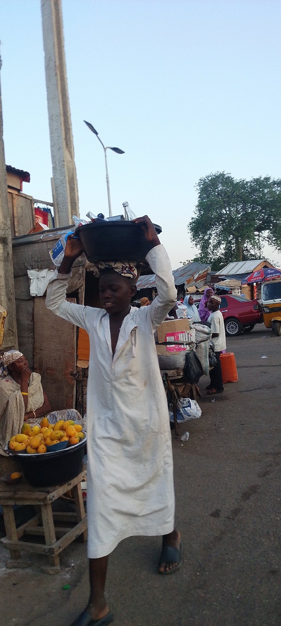 Street vendor carries bottles in Lokoja market area