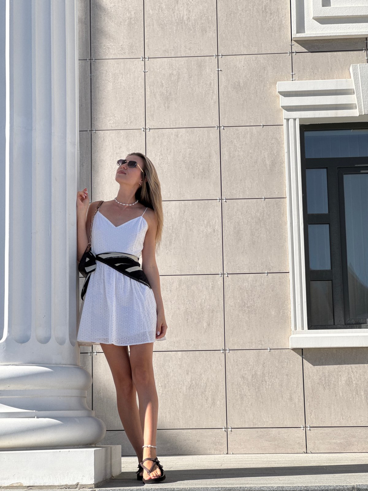 Woman in white dress visits classical courthouse building area