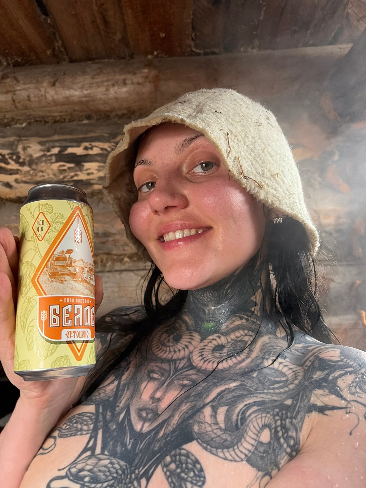 Person with tattoos holds beer in Russian town