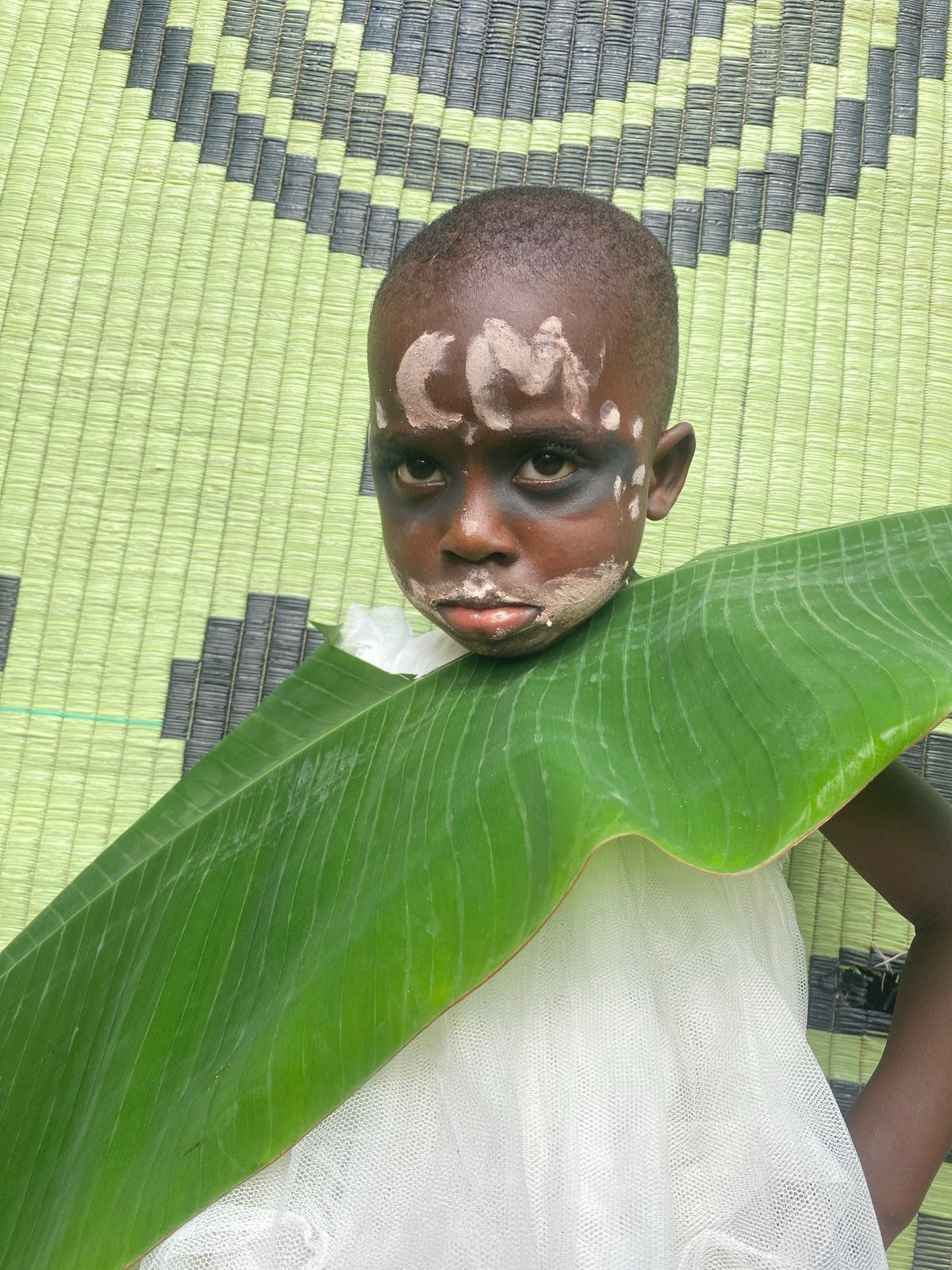 Child with ceremonial face paint rests in Nigerian village