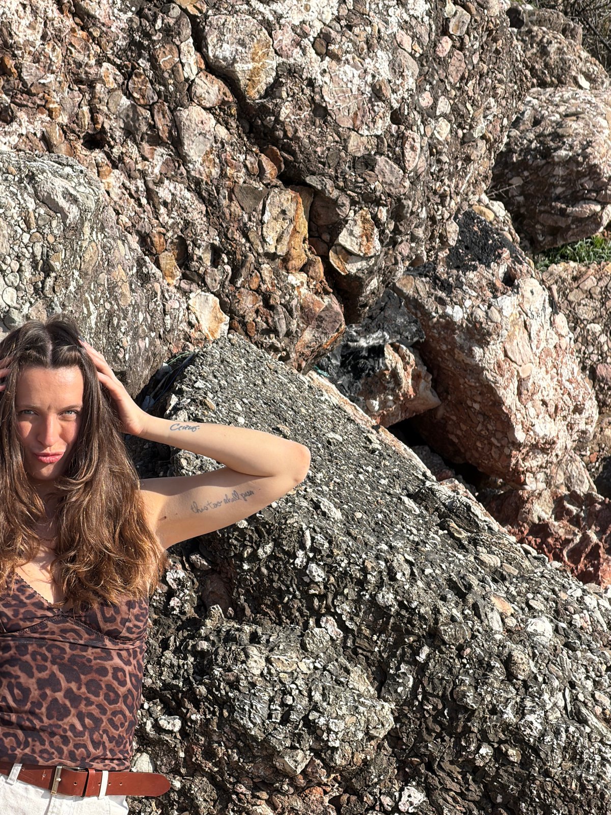 Woman rests on rocks in Sveti Stefan, Montenegro