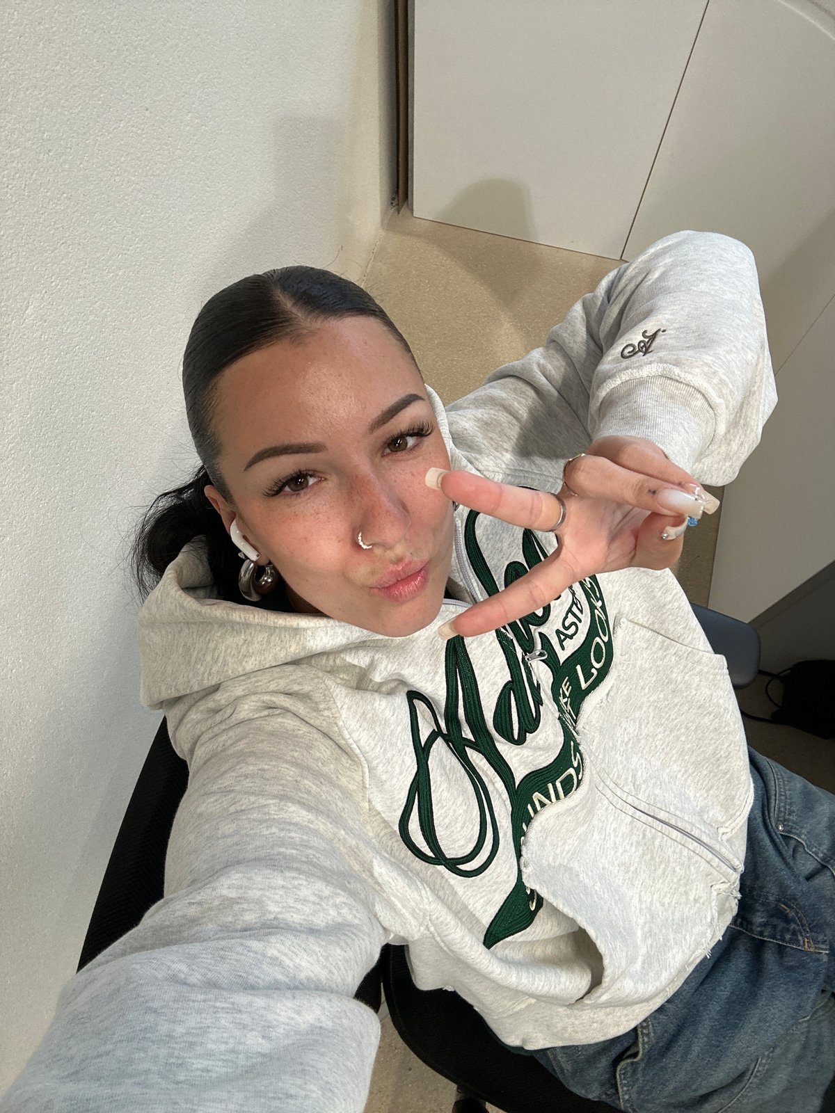 Woman poses for selfies in Paris wearing gray hoodie