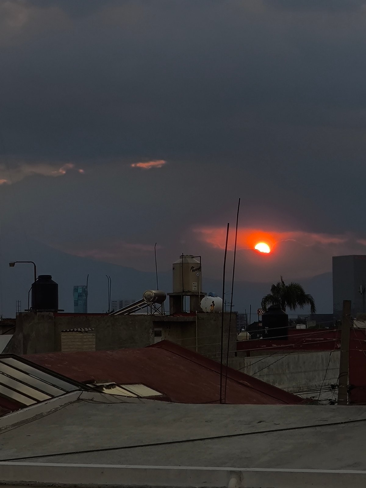 Dramatic sunset observed over Puebla rooftops amid stormy clouds