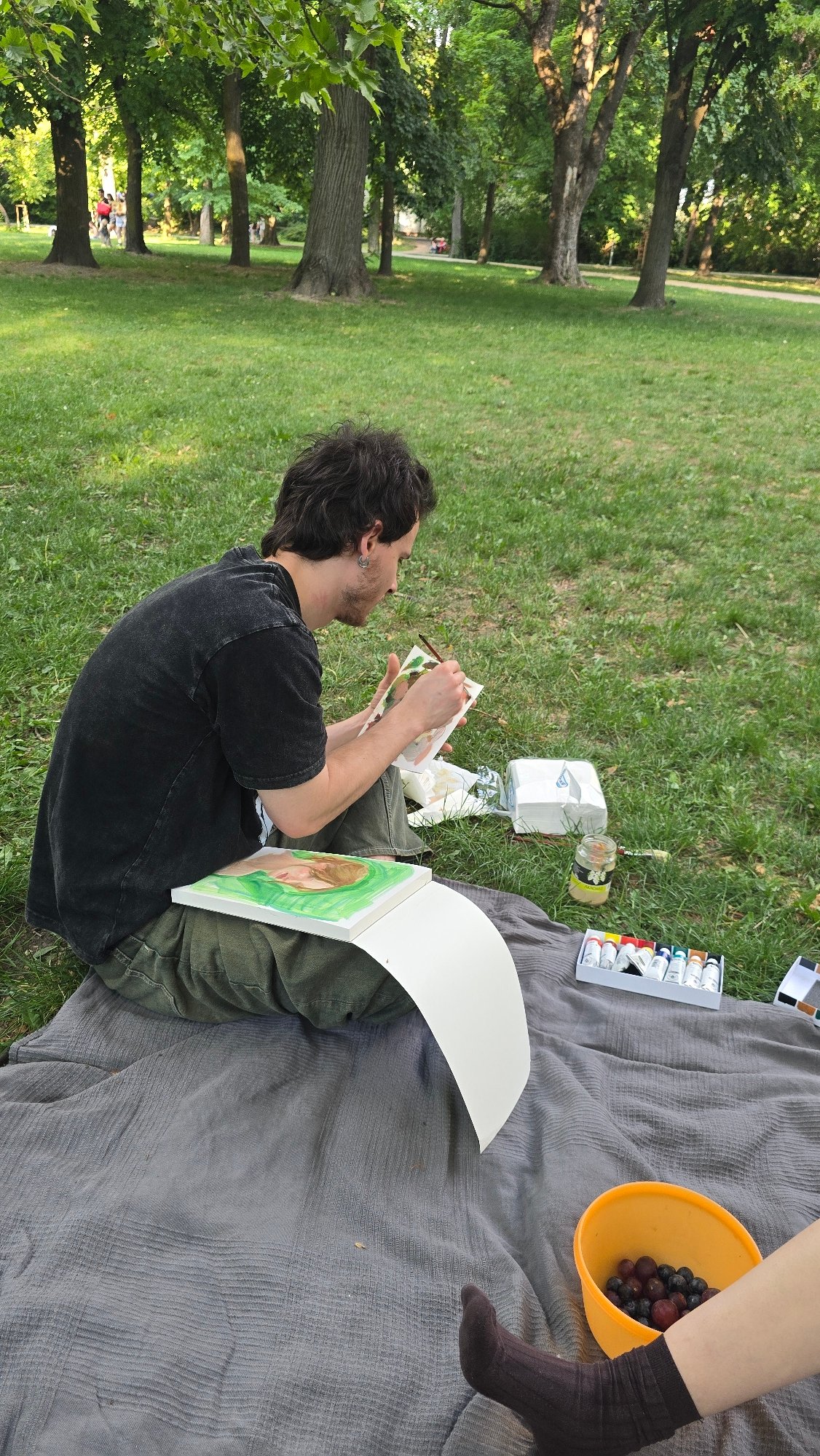Artist paints outdoors in Budapest park on sunny afternoon