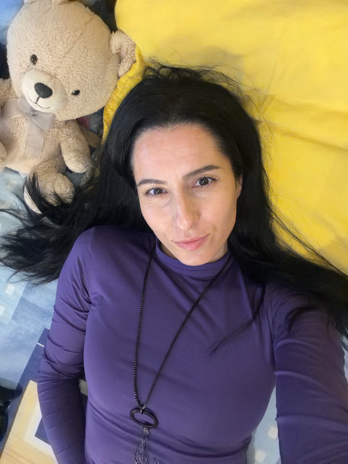 Woman poses with teddy bear on bed in Bulgaria