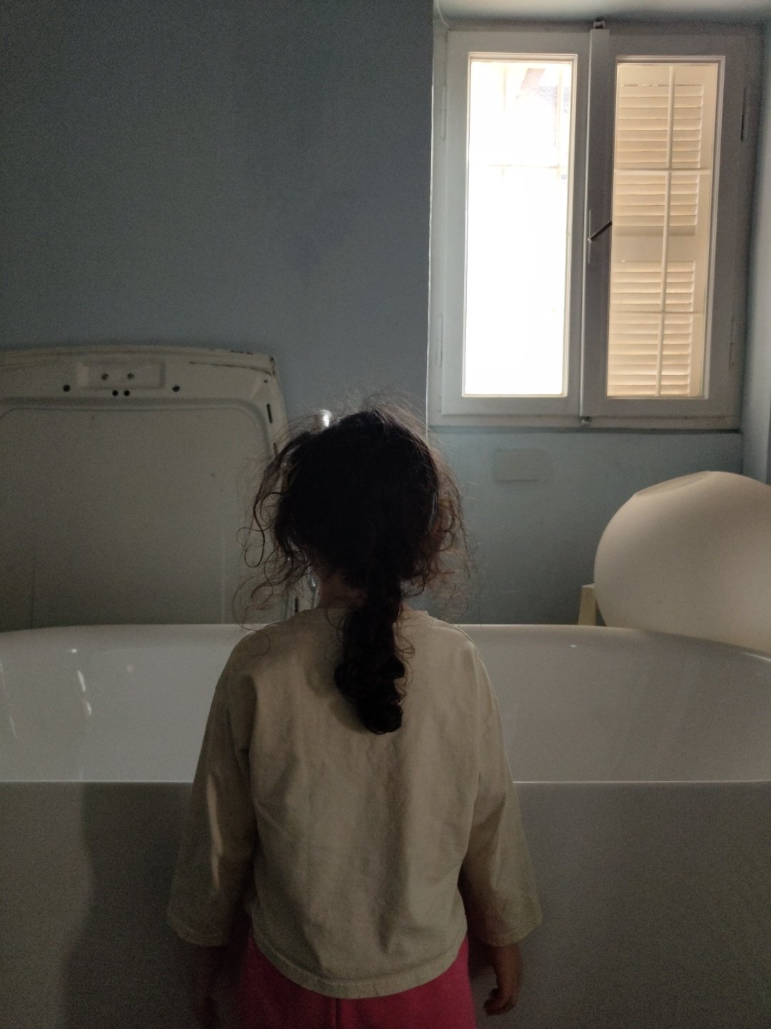 Young person observed in bathroom interior near toilet and sink