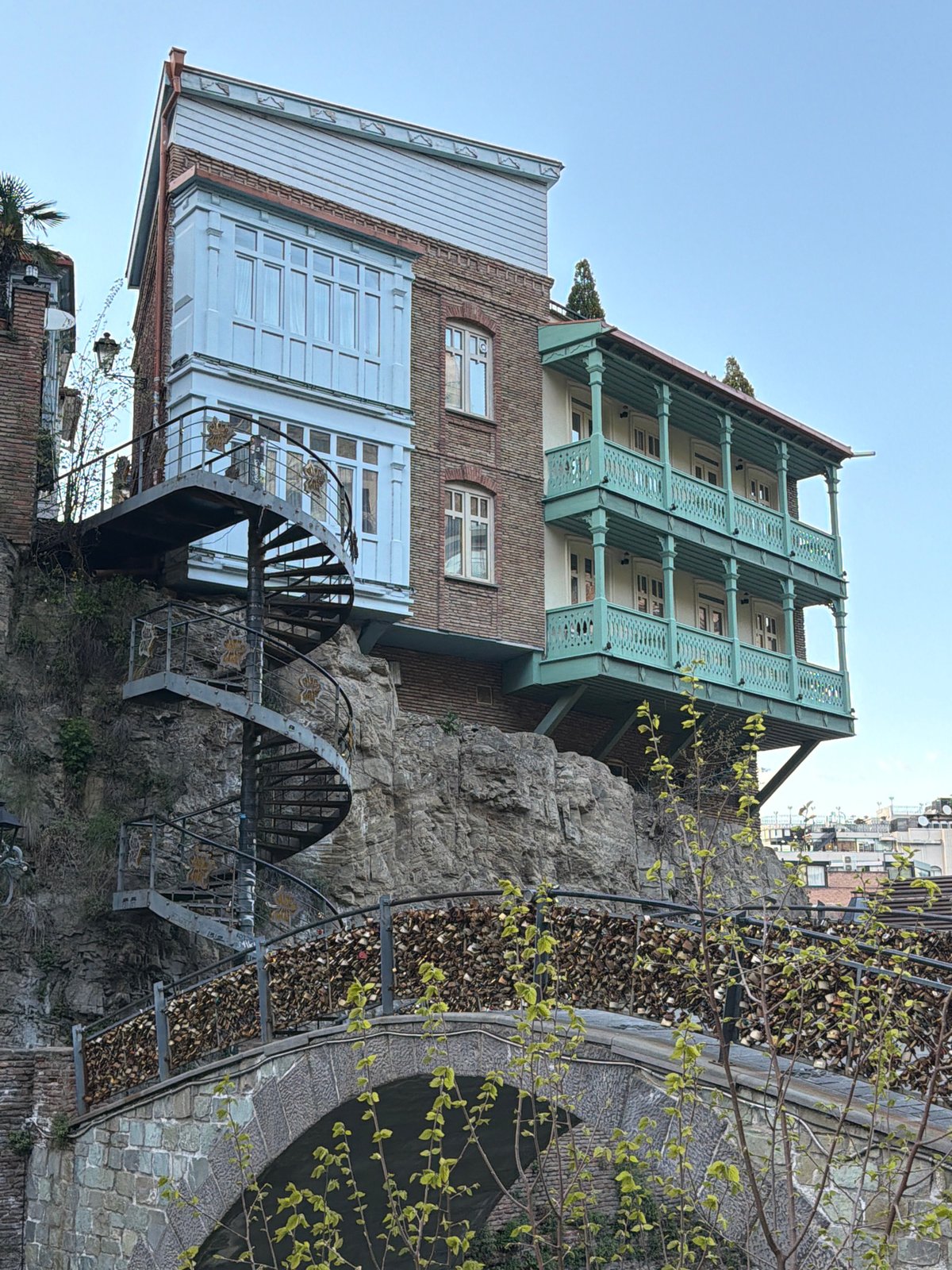 Multi-story cliff building with green balconies documented in Tbilisi