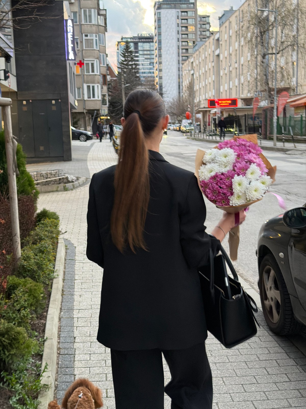 Woman with flowers walks near Sofia hospital at dusk