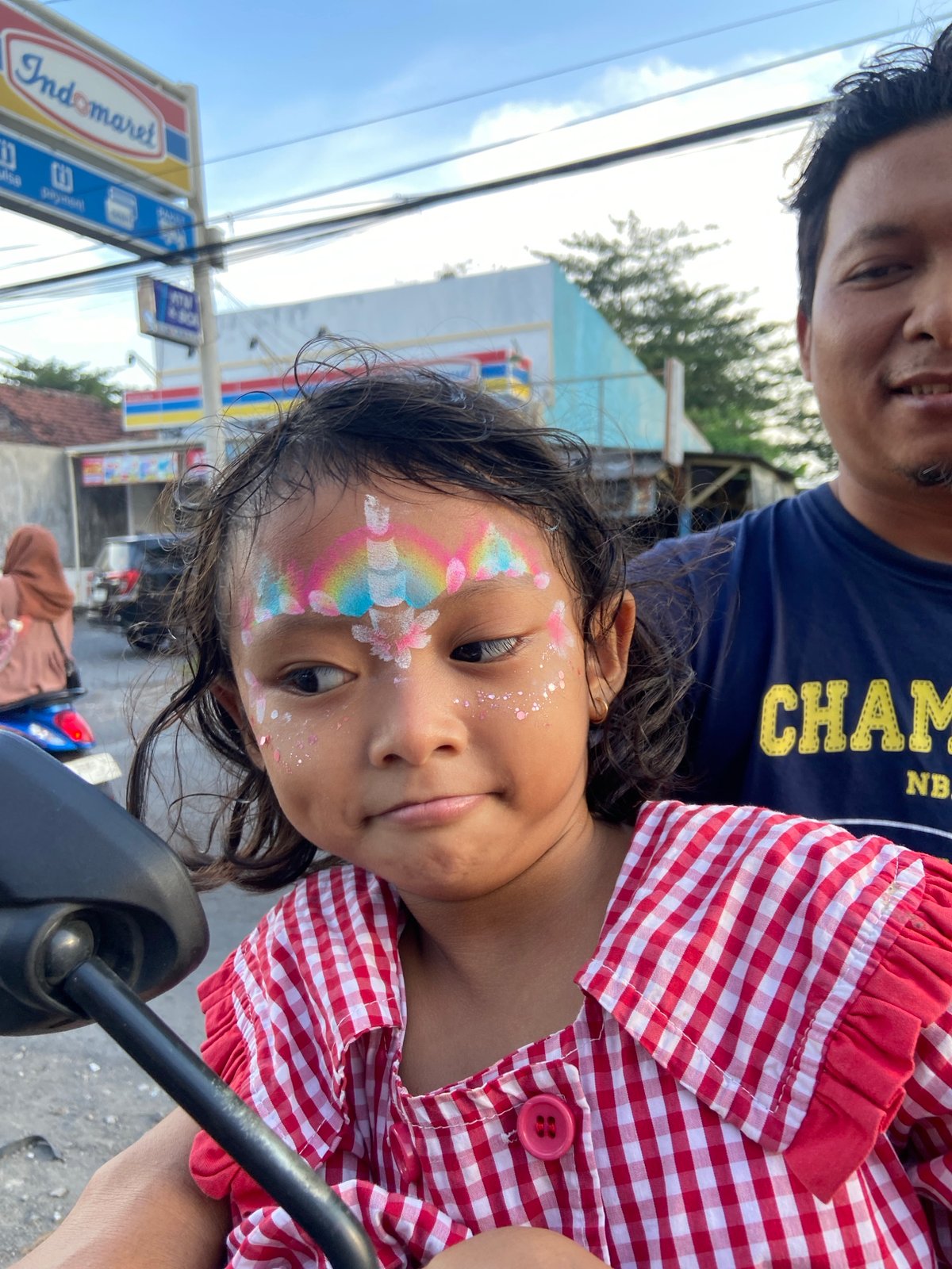 Father, daughter with face paint ride motorcycle in Indonesia
