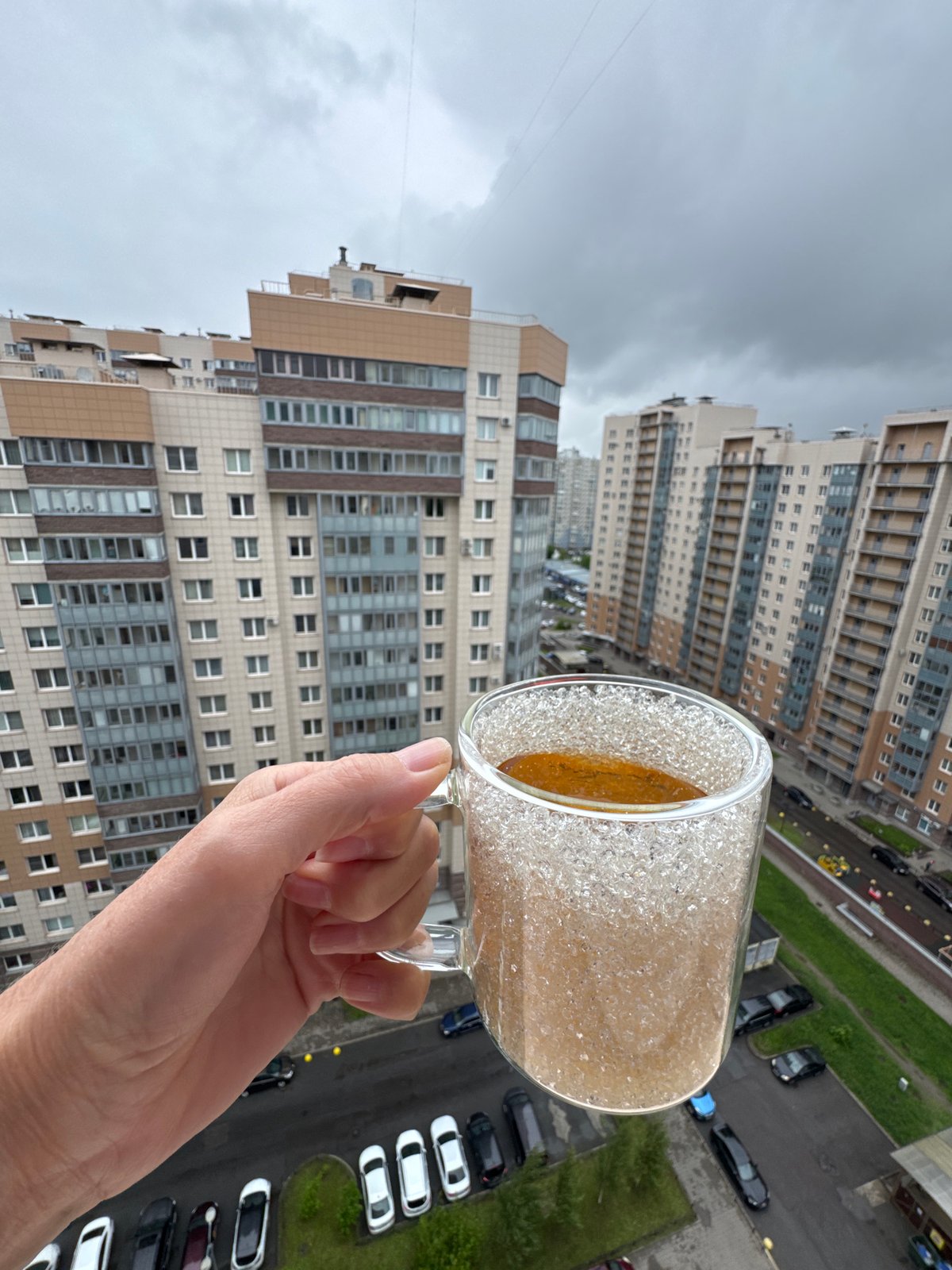 Person holds specialty tea drink amid urban overcast morning