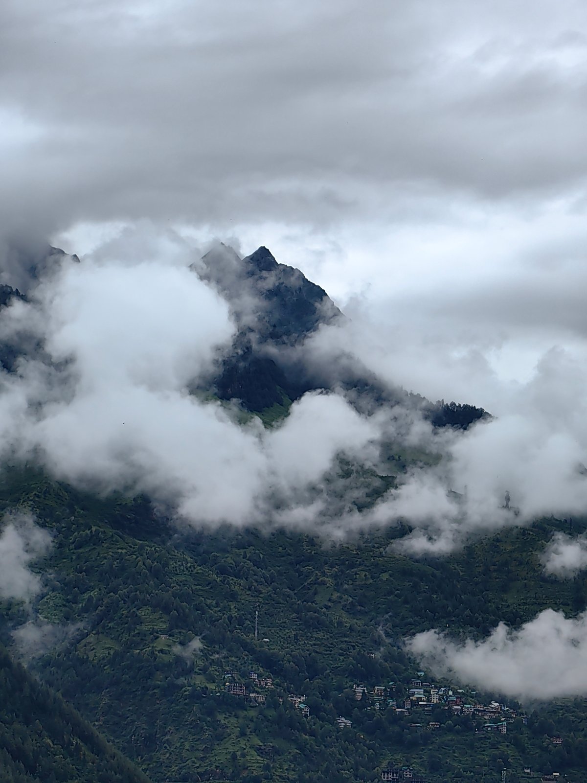 Misty morning over Vashisht's forested mountains and village