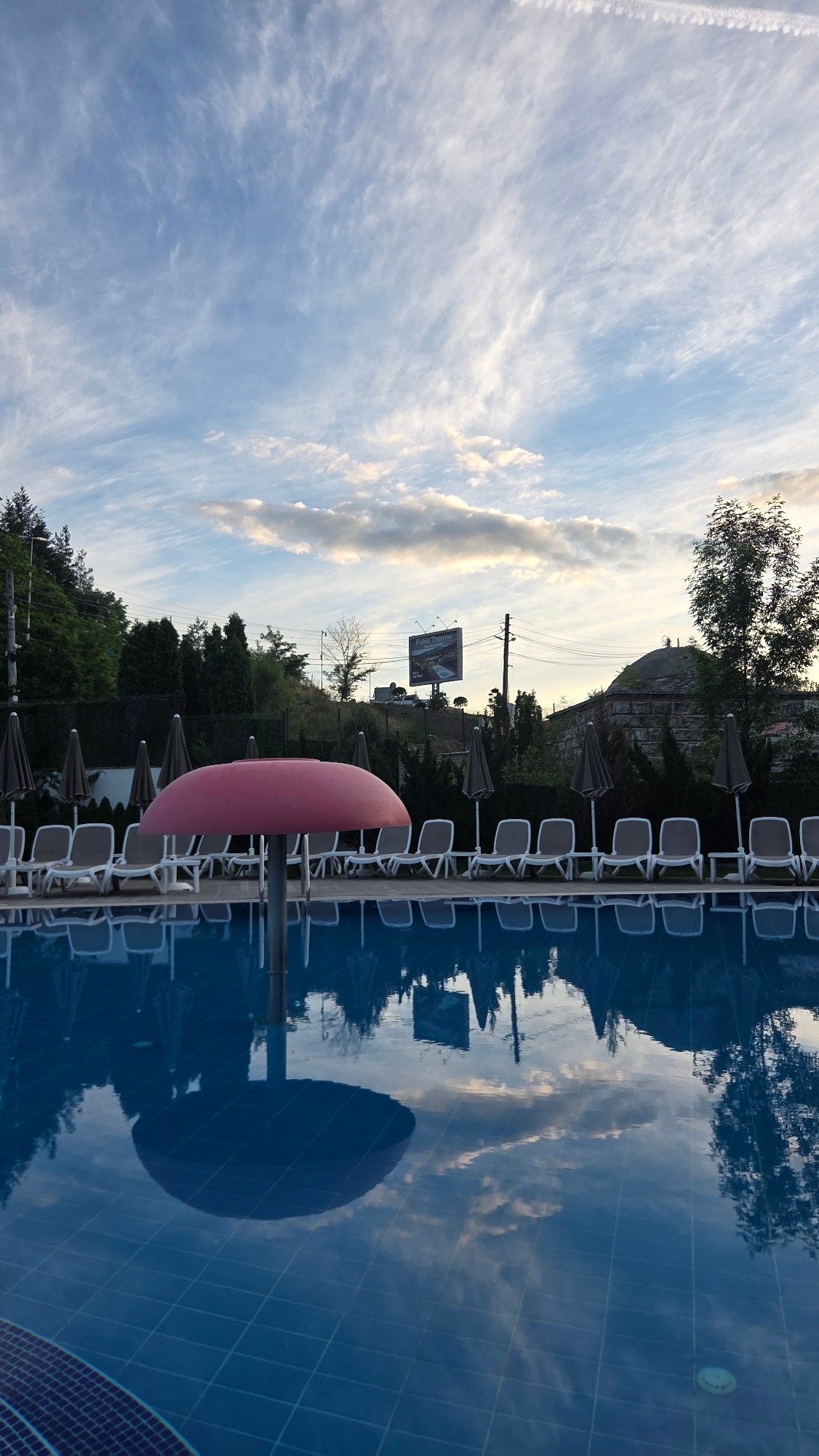 Aiper robotic pool cleaner beside a backyard pool at dusk