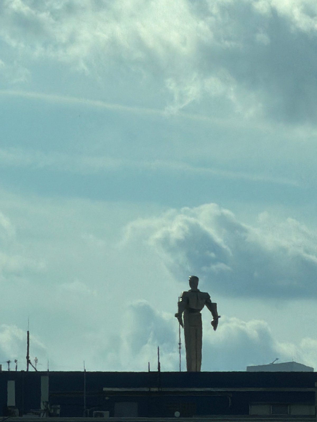 Suited statue silhouetted atop a Moscow industrial building