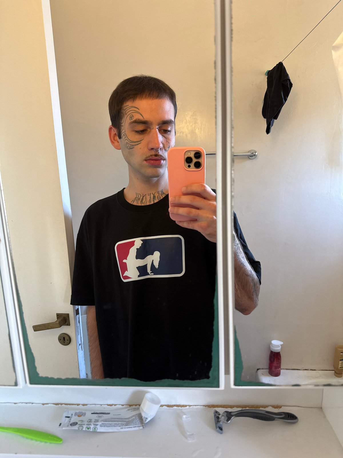 Man with facial tattoos takes bathroom mirror selfie in Buenos Aires