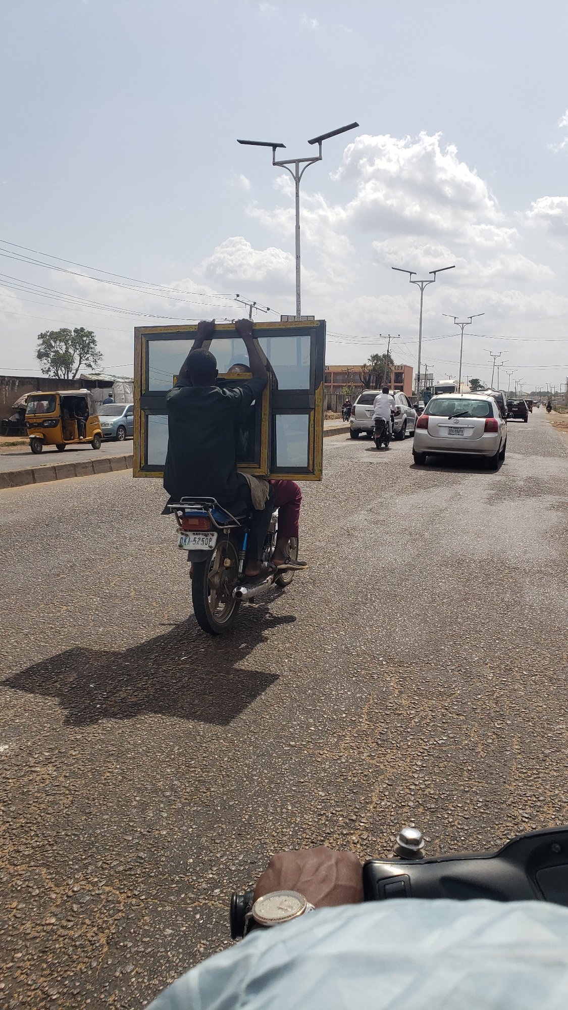 Motorcyclist carries large window frame on Nigerian road