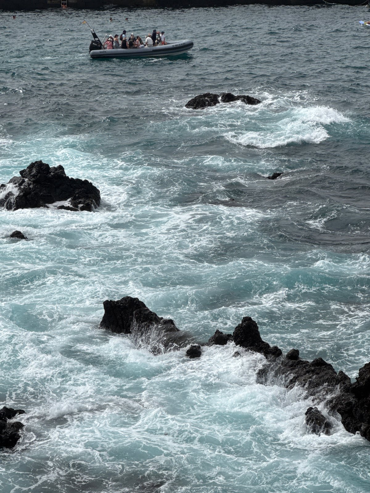 Overcast coastal day: waves, promenade life, and boats
