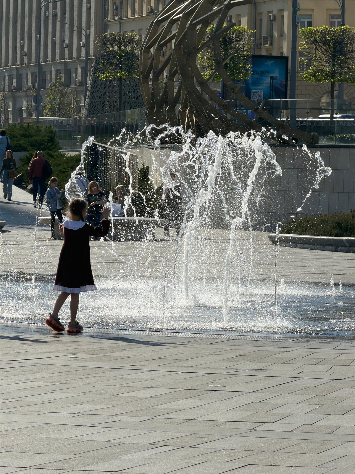 Girl in red dress interacts with water in Moscow