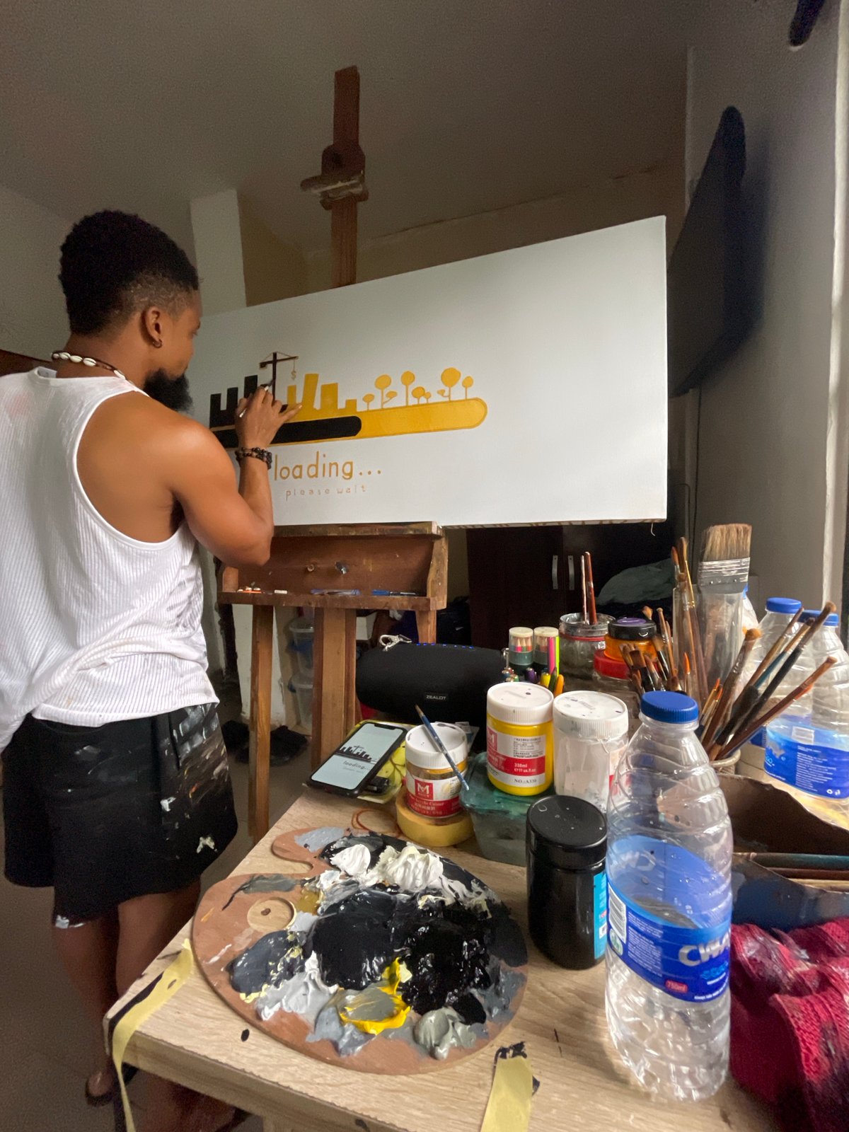 Artist paints "loading" cityscape canvas in Ado studio