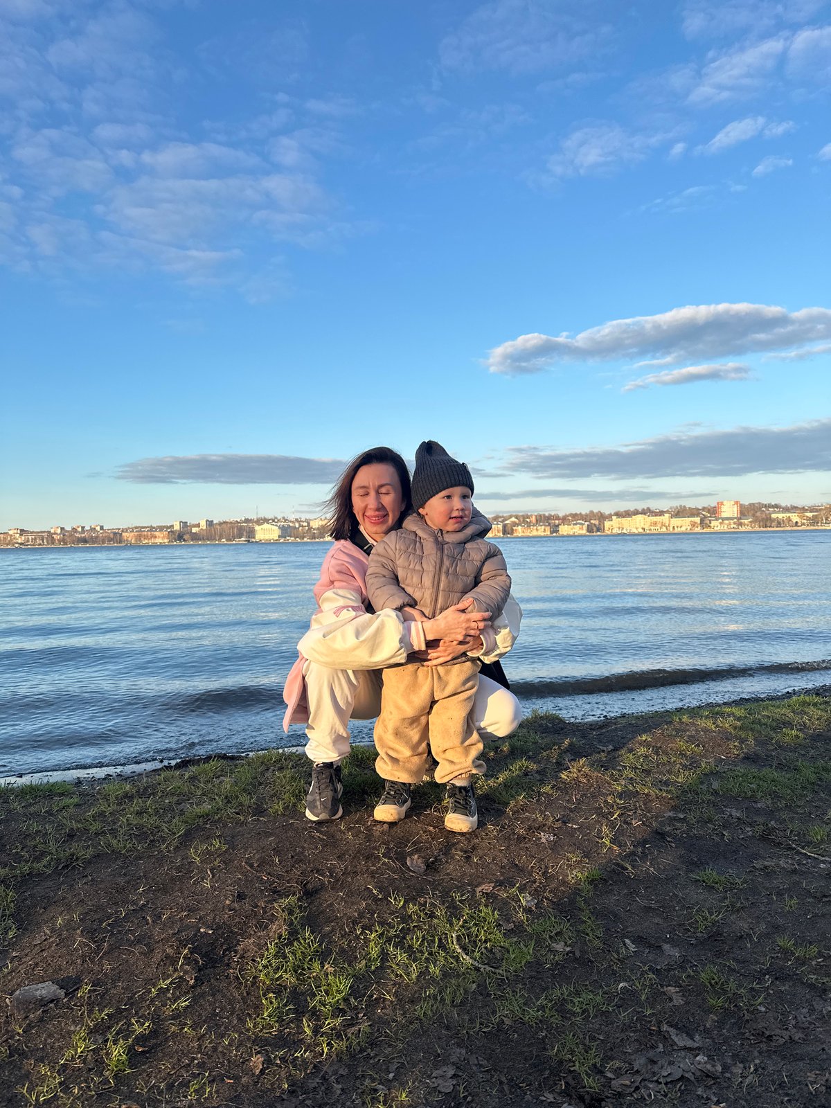 Woman, child rest together by waterside in Votkinsk