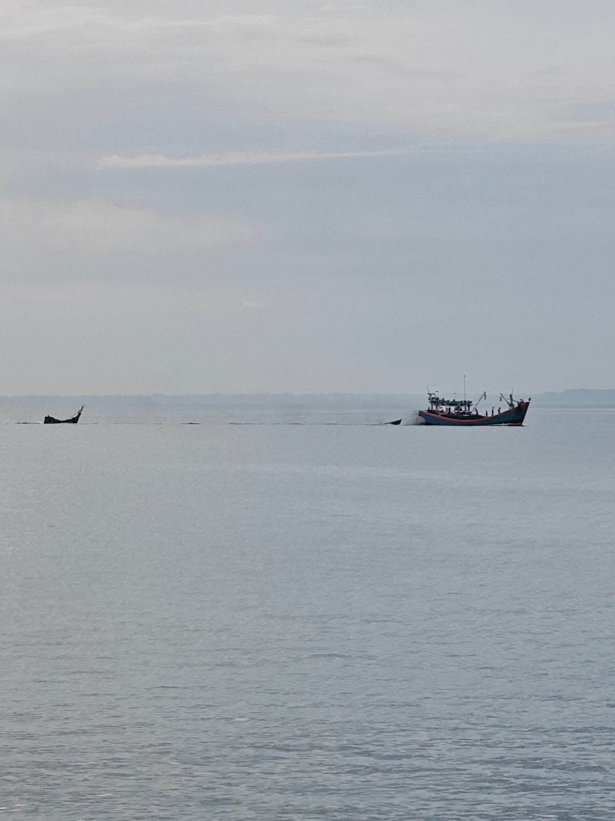 Lhokseumawe waterfront at dusk: pier, fishing boats, and shoreline