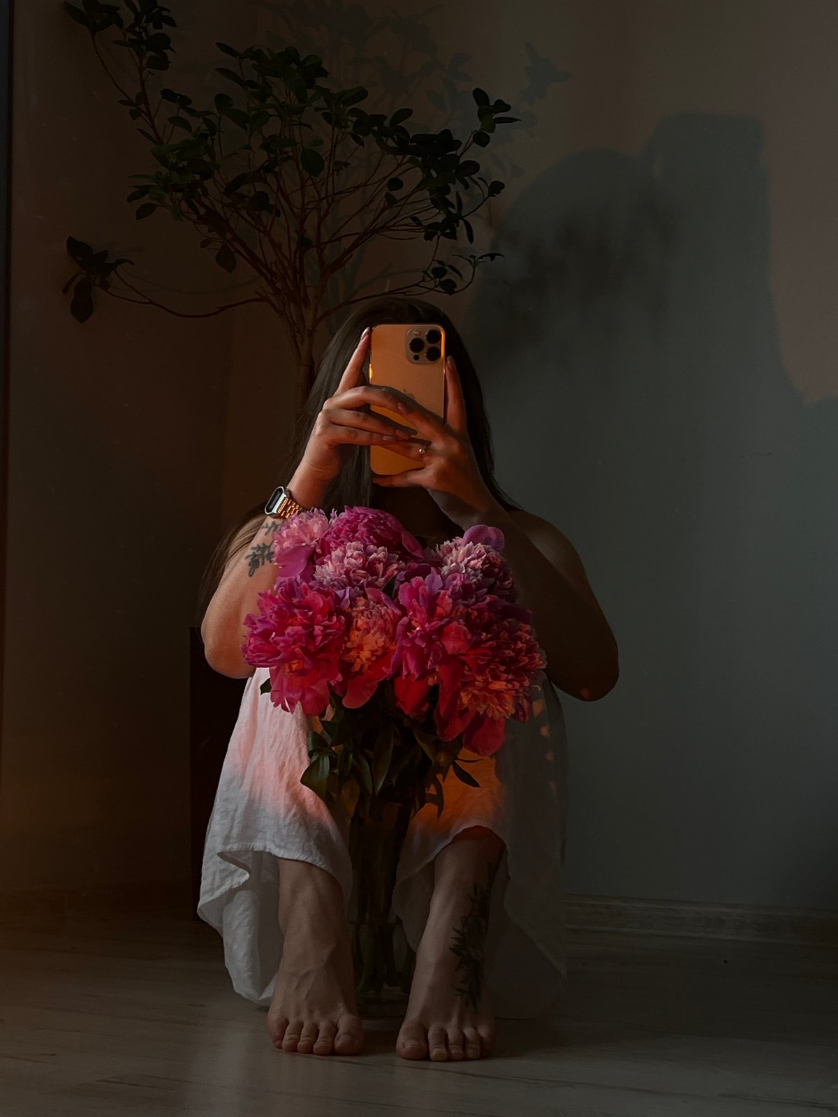 Woman takes selfies with pink peonies in Ternopil room