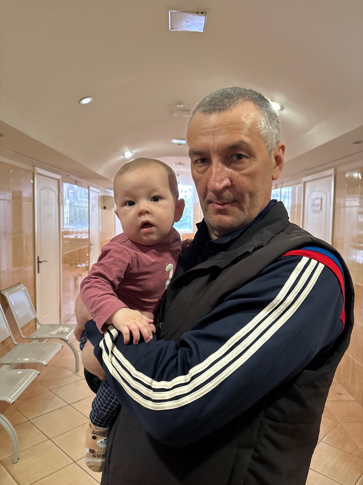 Man holds baby in Sochi medical facility waiting area