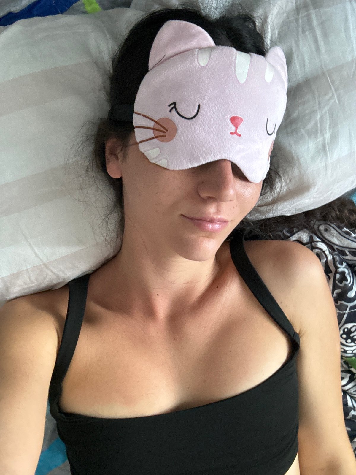 Woman with cat sleep mask shares bed with pets