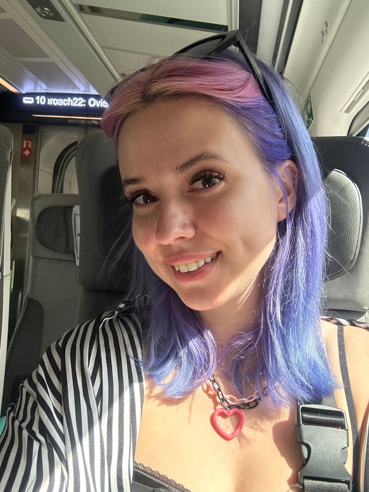 Woman with colorful hair photographed smiling on Spanish train