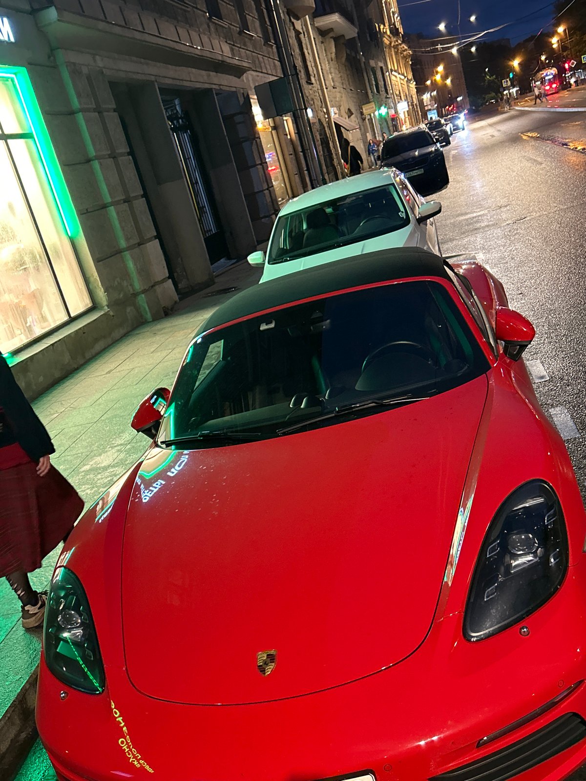Red convertible parked on rainy city streets after dark