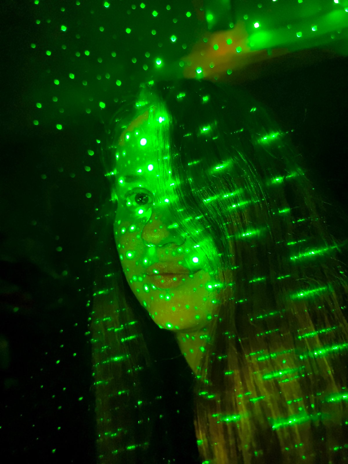 Person and hand captured in green laser light display