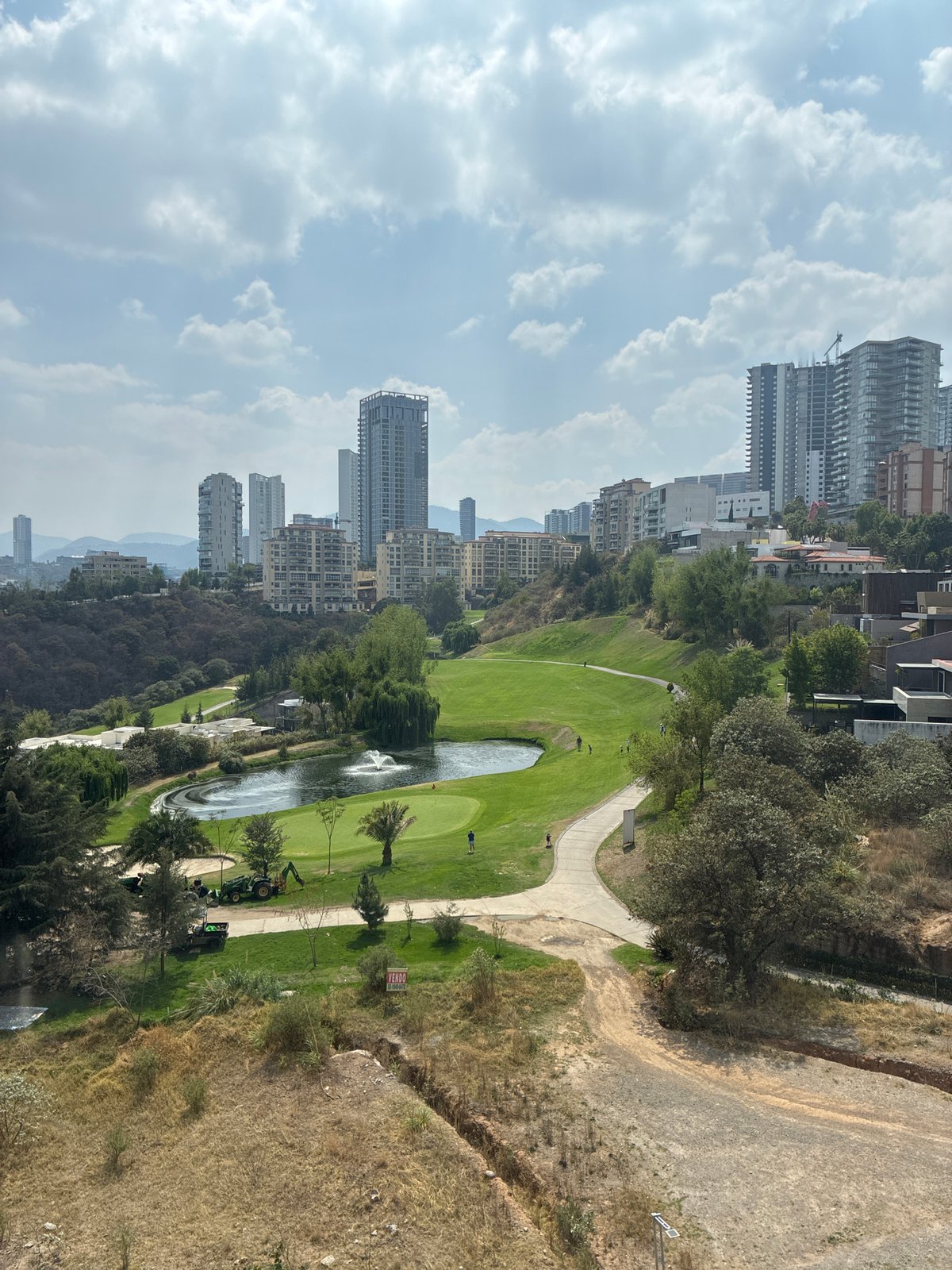 Person smoking at elevated viewpoint overlooking Huixquilucan golf course