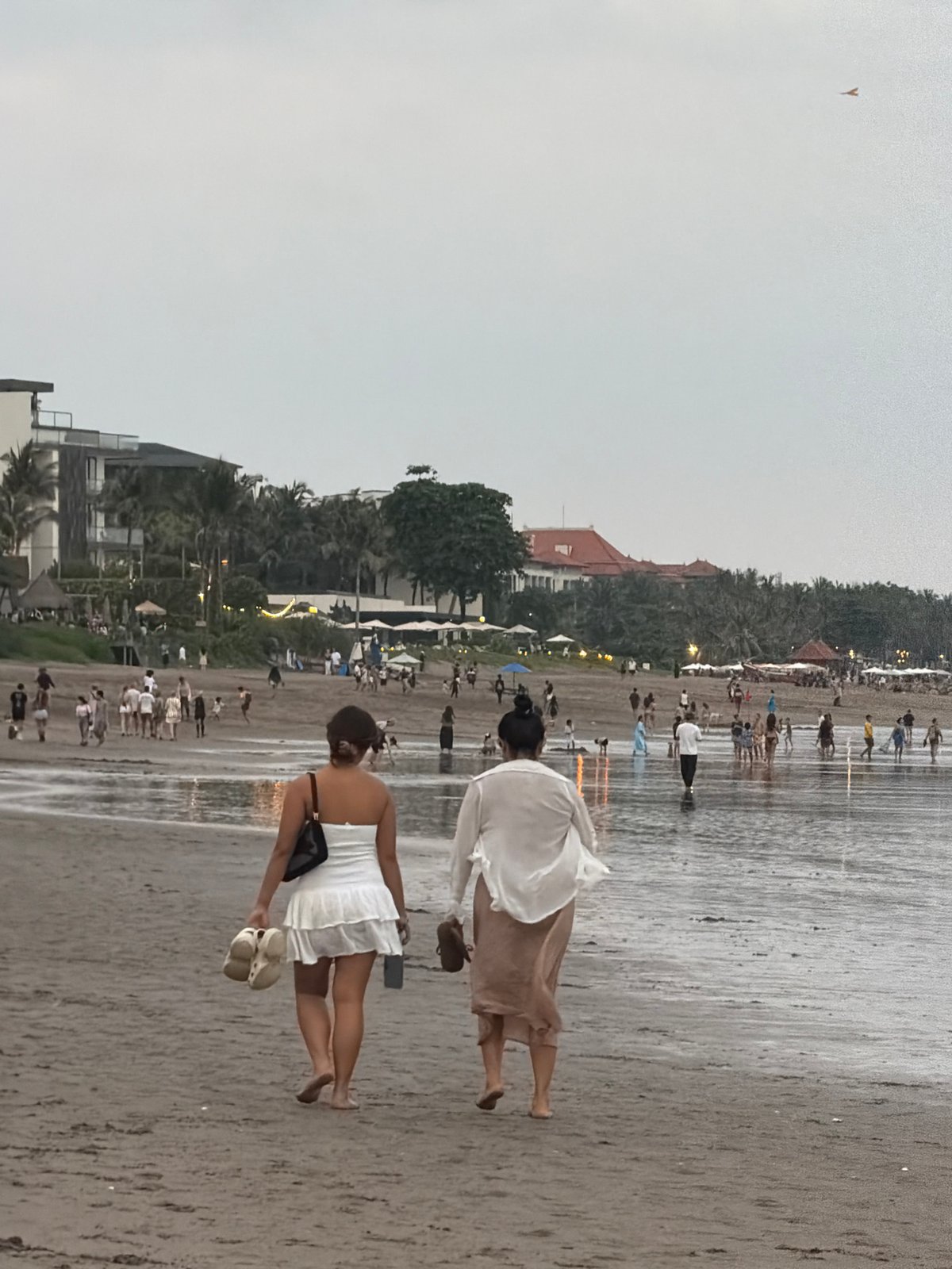 Overcast morning on a North Kuta beach, people in the surf