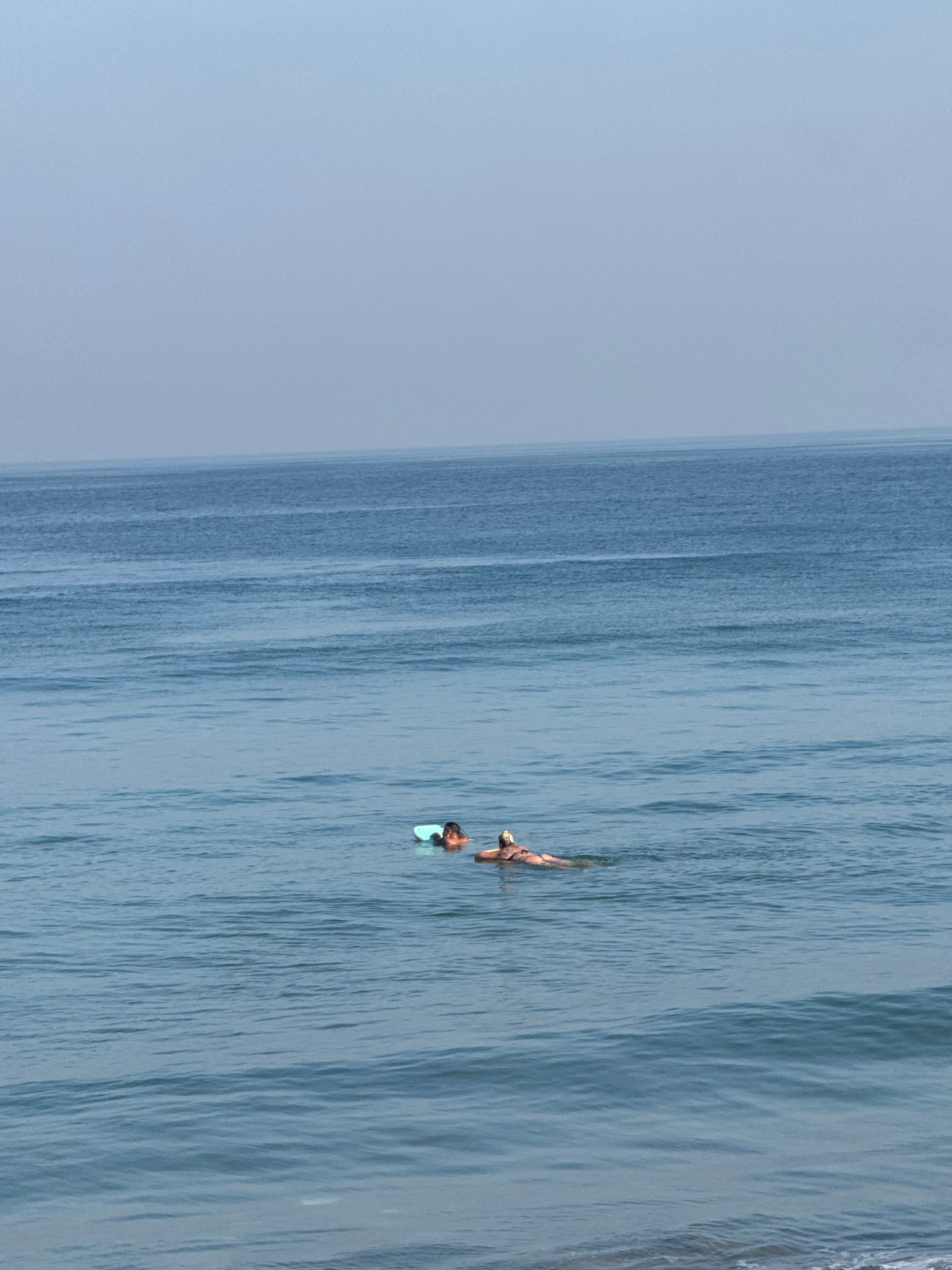 Surfers and swimmers out at Kuta Beach on a sunny afternoon