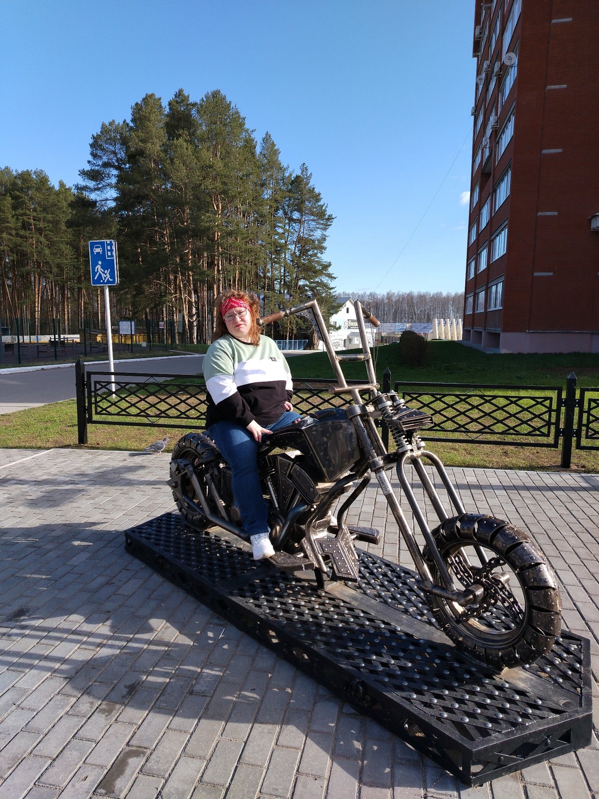 Woman poses on motorcycle sculpture in Chaikovsky, Russia