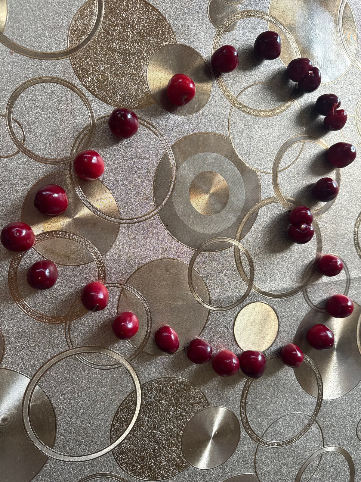 Red cherries scattered on decorative metallic surface