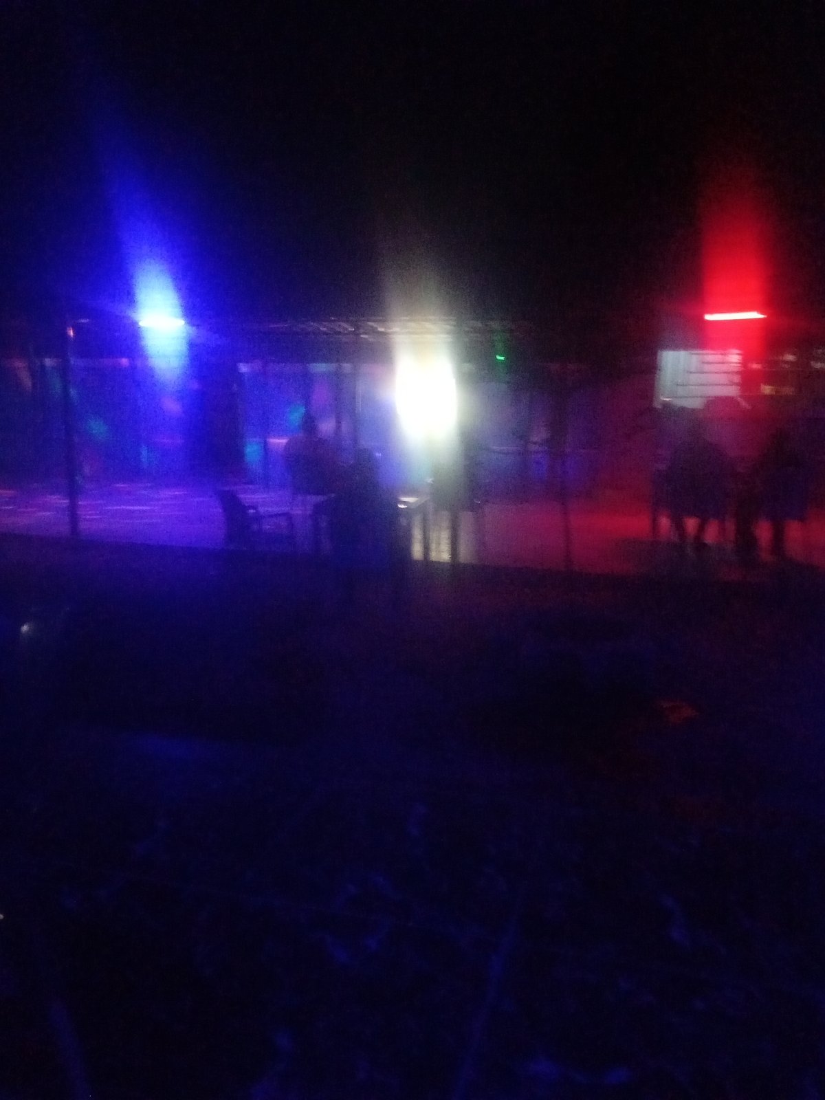 Nighttime outdoor venue illuminated by vibrant colored lights draws crowds