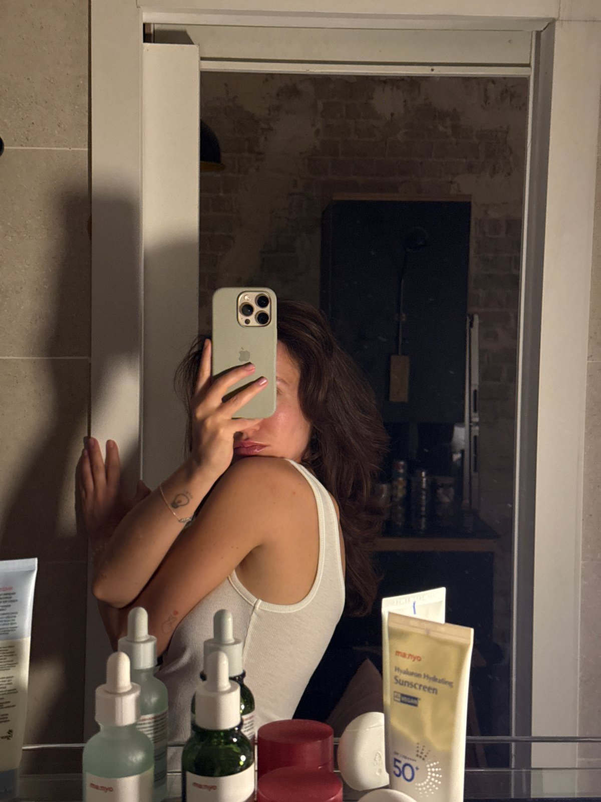 Bathroom mirror selfie in Tel Aviv with skincare products nearby
