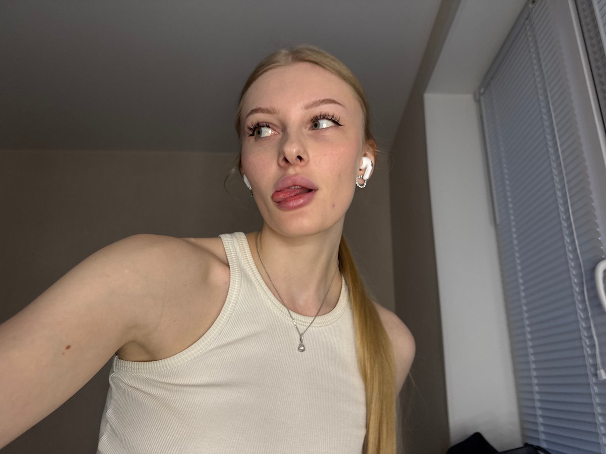 Woman takes multiple selfies at lighted vanity mirror in Perm