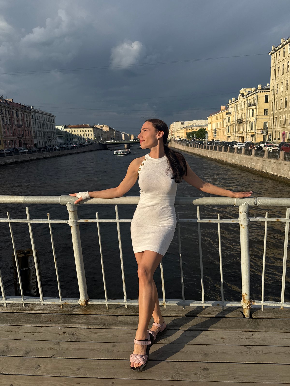 Woman poses dynamically on Saint Petersburg pier overlooking waterway