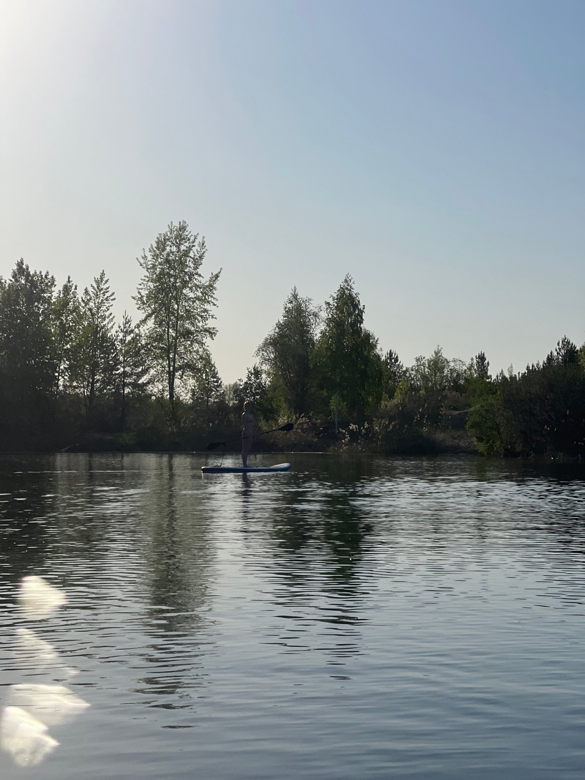 Paddleboarder enjoys sunny afternoon on lake near Novyi, Russia