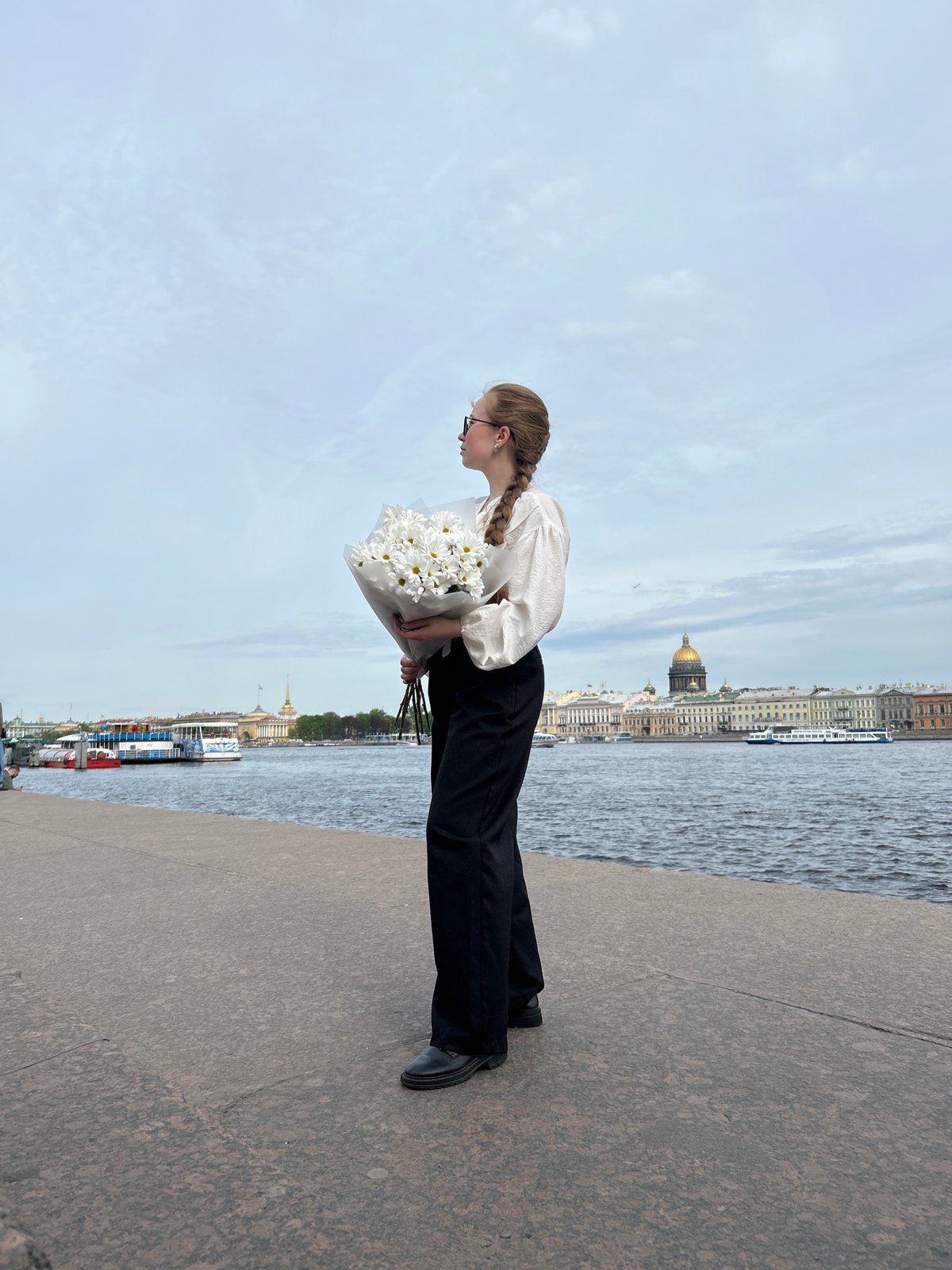 Woman with white flowers walks Saint Petersburg embankment