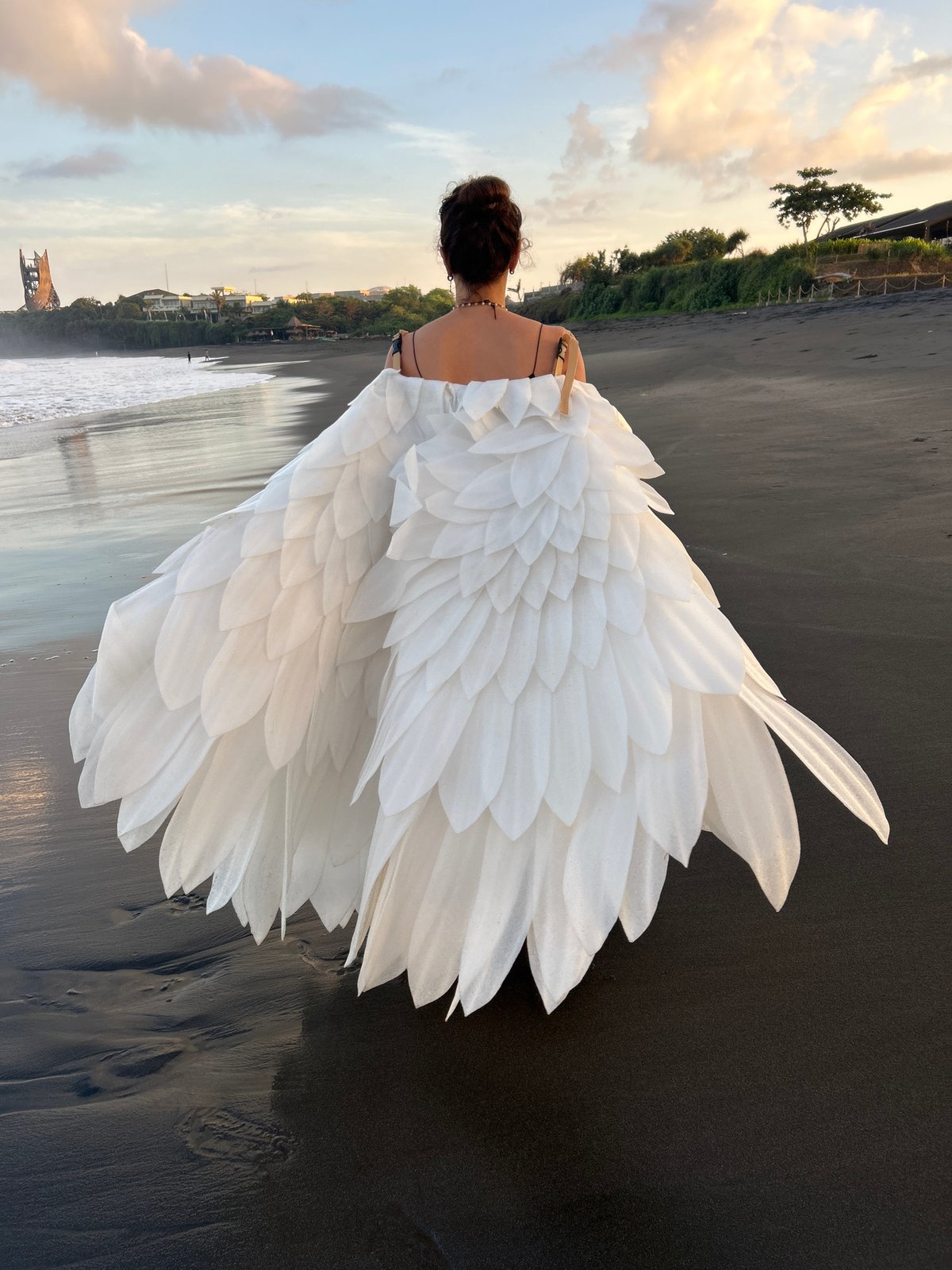 Winged figure walks beach at sunset in Bali